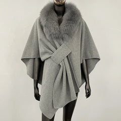 Grey knit poncho with a grey fur collar and knotted front.