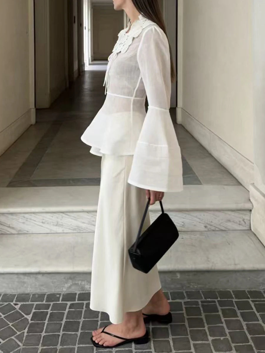 Person wearing a white outfit with bell sleeves in an indoor setting