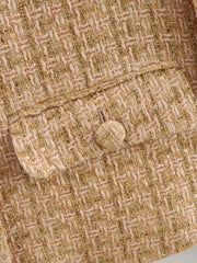 Close-up of textured fabric with a button, featuring a herringbone pattern.
