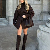 Woman wearing a brown coat and knee-high boots in an urban setting