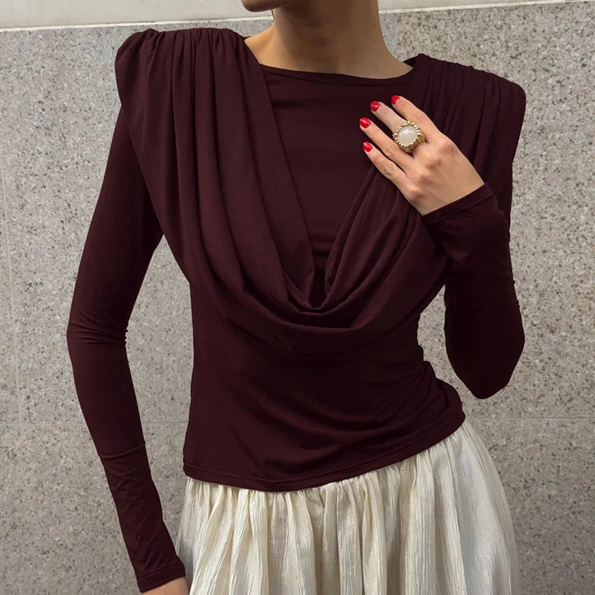 Person wearing a burgundy long-sleeve top with a plain background