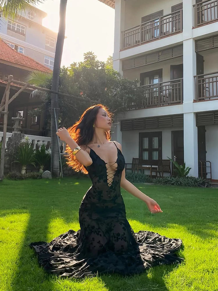Woman in a black dress standing on grass with a building in the background