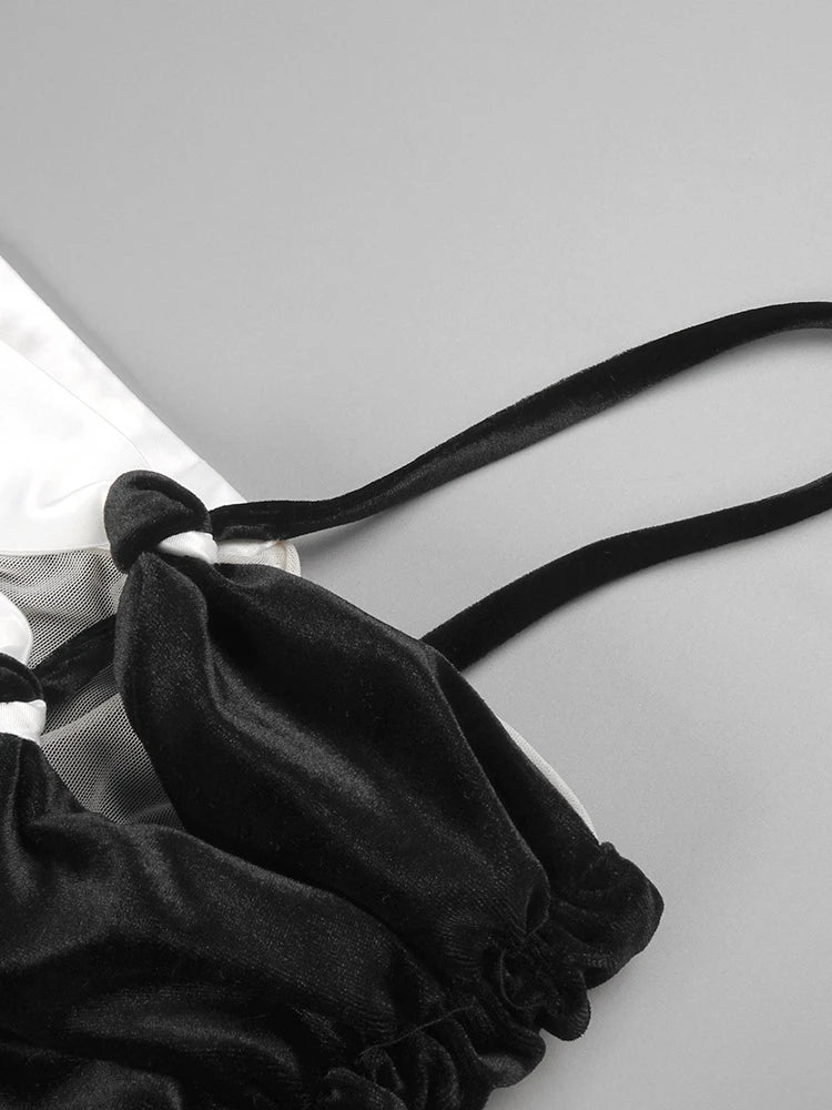 Black satin lingerie set with a strap on a light gray background