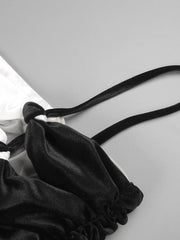 Black satin lingerie set with a strap on a light gray background