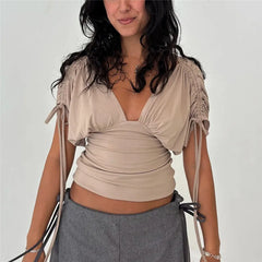 Model wearing a beige deep V neck ruched drawstring sleeve top