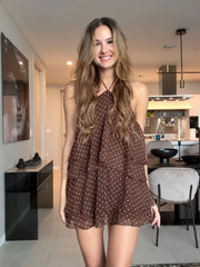 Woman in a brown polka dot dress standing in a modern kitchen.