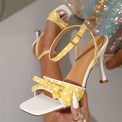 Close-up of yellow polka dot stiletto heels with bow
