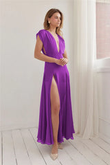 Woman wearing a purple dress with a high slit in a bright room.