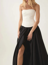 Woman in strapless white top with black puff skirt, front slit