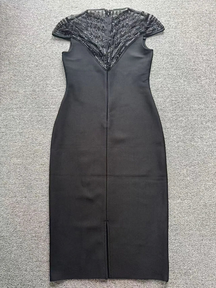 Flat lay of a black sheath midi dress with a beaded mesh yoke and cap sleeves.