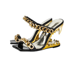 Black and gold high-heeled shoes with chain details on a white background