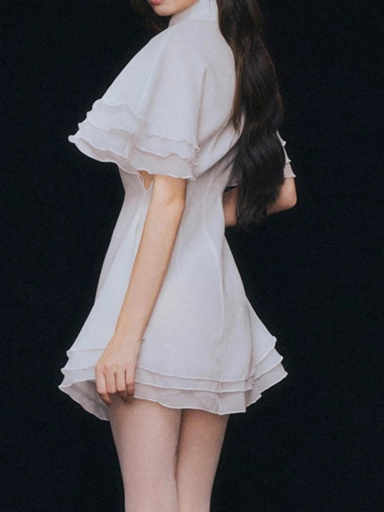 Side view of a woman wearing a
short ruffle hem mini dress styled for party nights s on a black background.