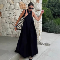Woman in black halter dress posing by stone wall in garden