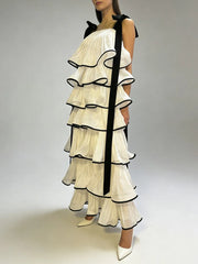 Side profile of tiered ruffle ankle length dress with graphic edge trim and sculpted A-line shape captured in motion on studio background