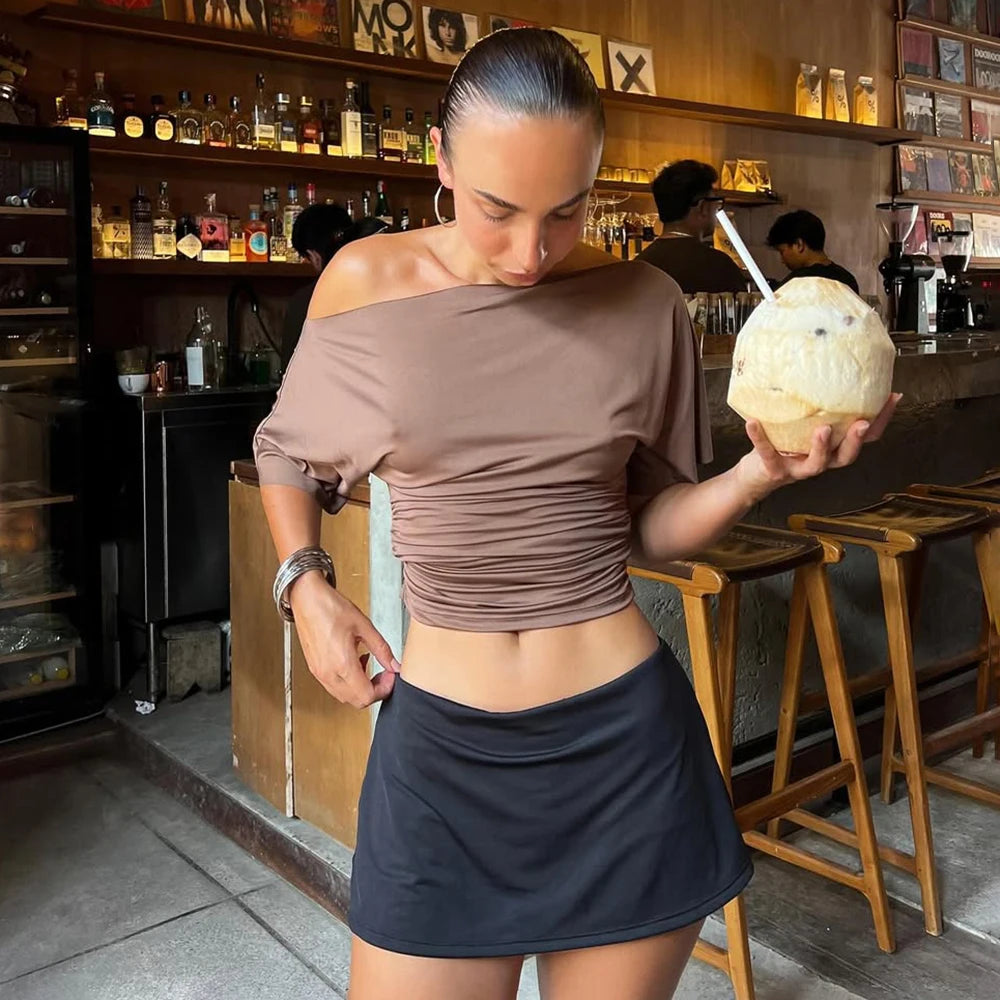 A woman wearing a solid, asymmetric ruched vest top styled for a casual outing.