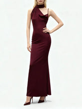 Full-length studio view of a model wearing an asymmetrical sheath dress with a clean ankle-length drape and minimalist evening posture.