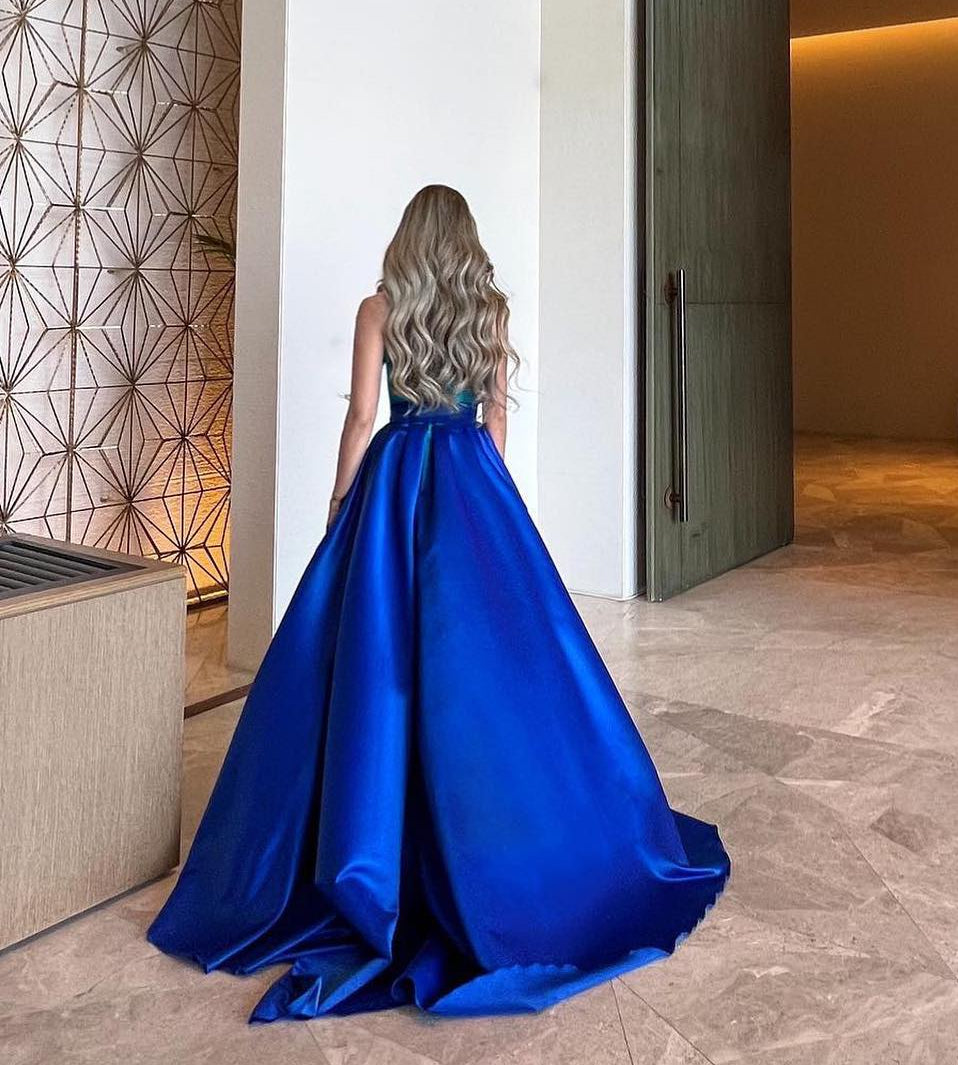 Woman in a blue evening gown standing in a modern interior setting