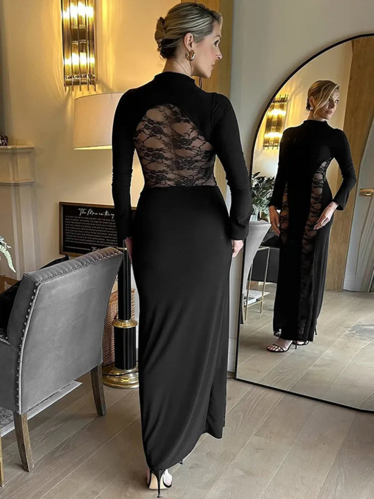 Woman in a black dress with lace detailing standing in front of a mirror.