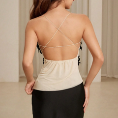 Backside view of a woman wearing a beige top with a criss-cross back design in a neutral setting