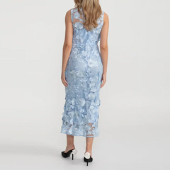 A woman wearing a pastel blue gown with a high waist and floral texture on a white background.