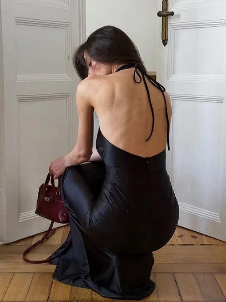 Woman in a floor-length satin sheath dress for formal events sitting on the floor with a red handbag next to her.