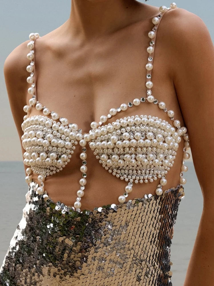 Silver sequin midi dress styled for an evening beach setting, showing fluid movement and reflective texture.