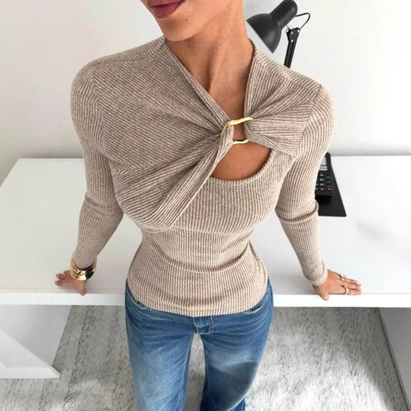 Overhead angle of a beige rib-knit top with an asymmetric wrap and keyhole cut-out, styled with blue jeans indoors.