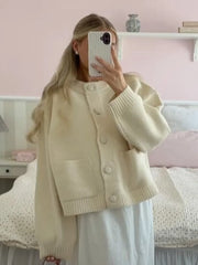 Person wearing a beige cardigan in a bedroom setting