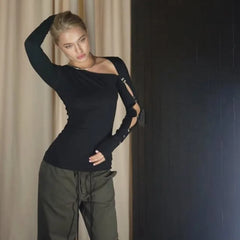 Waist-up angle of a black asymmetric top showing clean drape through the torso and the neckline’s sharp, angled finish.