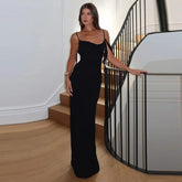 Woman in a Sleek black maxi dress with open back styled for evening standing on a staircase