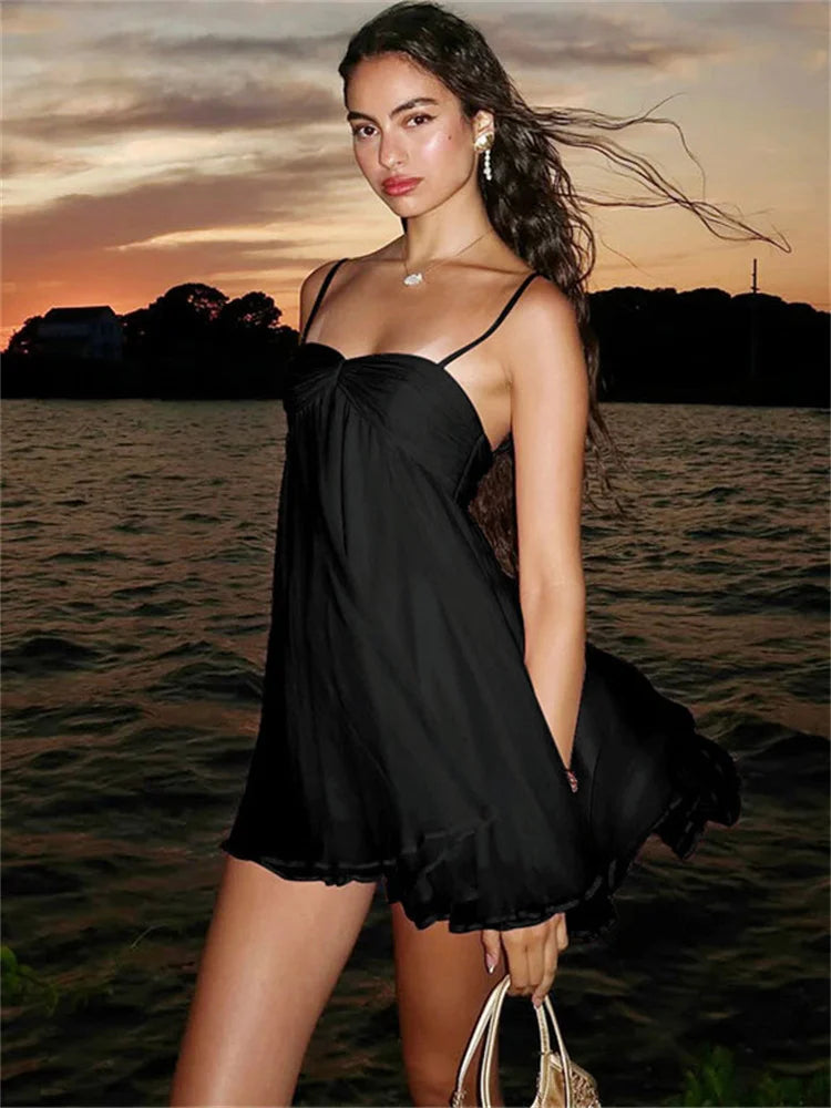 Woman in black backless mini dress with ruffled hem at sunset
