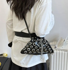 Close-up of metal eyelet rivets across the black bag, showing the glossy finish and hardware pattern in crisp detail.