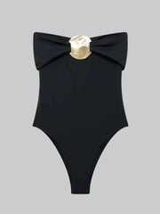 Close-up of the folded off-shoulder neckline and metal hardware, showing the smooth fabric finish and structured drape across the top edge.