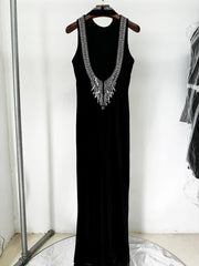 A black floor-length halter dress with a deep open back and slim silhouette.