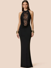 Model wearing a black halter maxi dress with a lace plunge neckline, styled with gold bangles against a soft beige studio background.