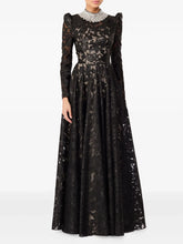 Black floor-length maxi dress with stand neckline and long sleeves, featuring embroidered texture and a fitted bodice before a flowing skirt.