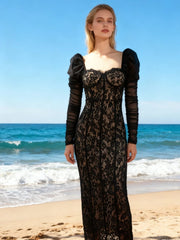 Woman wearing a black lace evening dress on a beach at sunset