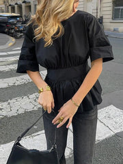 Person wearing a black outfit with a city street background