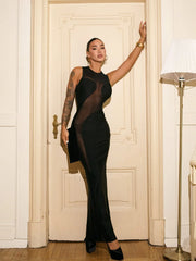 Woman wearing black mesh patchwork sheath maxi dress in elegant setting standing in a room with a white door and lamp.