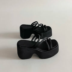Black platform heel slippers with narrow straps styled indoors