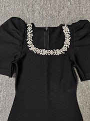 Black dress with floral neckline on a textured surface
