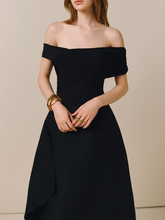 Black off-shoulder dress worn by a model against a beige background