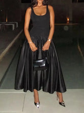 Woman wearing sleeveless black square neck midi gown at night
