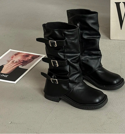 Black vintage buckle knee-high cowboy boots on gray surface