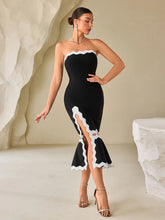 A woman wearing a Black and white strapless patchwork midi dress styled for cocktail parties. in a minimalistic setting.