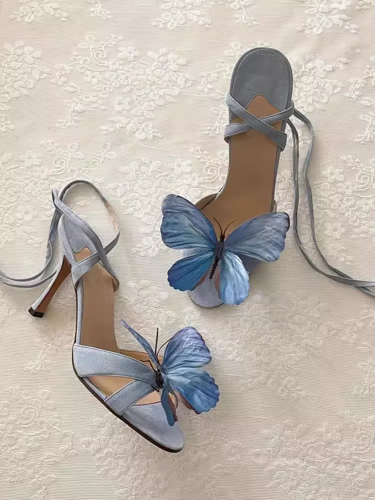 Blue high-heeled sandals with butterfly decorations on a light background
