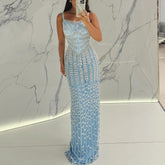 A woman wearing a blue spaghetti strap evening gown for a formal event.
