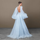 Back view of a light blue mermaid gown with a deep open back and soft draped panels falling from the shoulders.