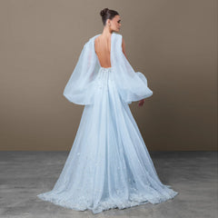 Back view of a light blue mermaid gown with a deep open back and soft draped panels falling from the shoulders.