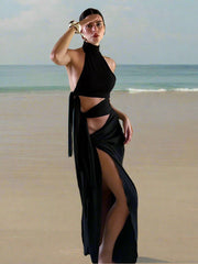 Woman wearing a Bodycon autumn sheath black maxi gown with dramatic high split for partiesn front of a brick wall.